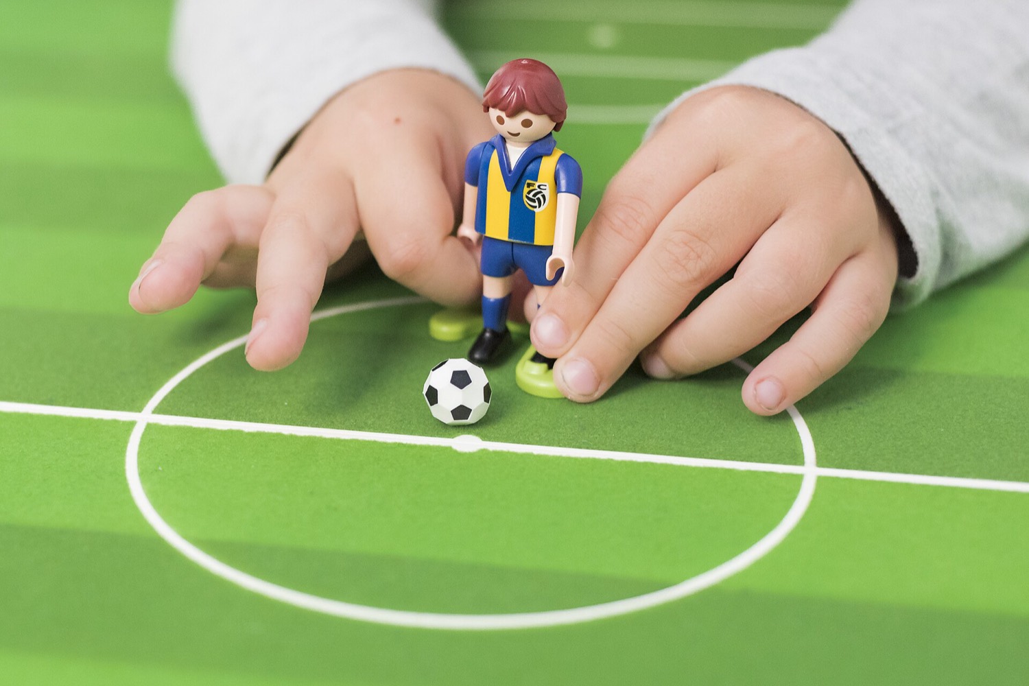 サッカーボールとフィギュアで遊ぶ子どもの手