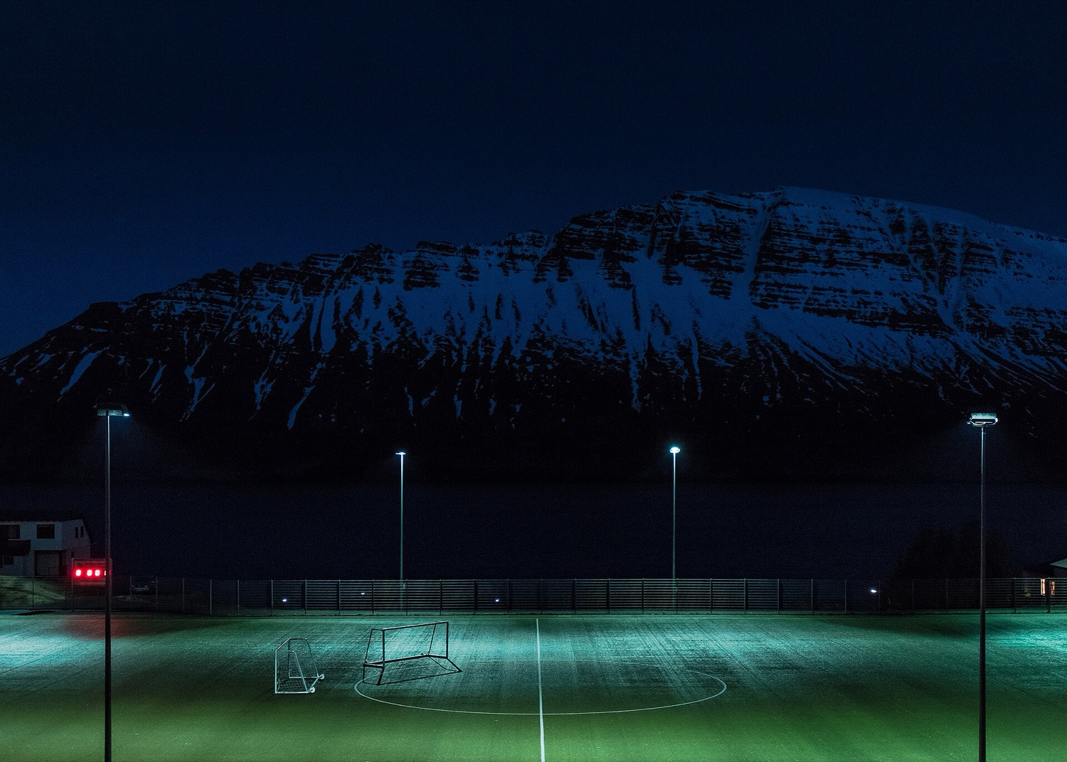 山のふもとにあるナイター照明のサッカーグラウンド
